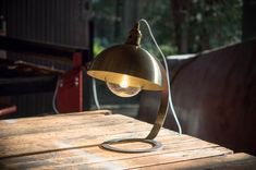 a lamp sitting on top of a wooden table next to a red chair in the background