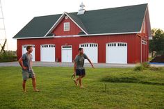 two men playing frisbee in front of a red barn