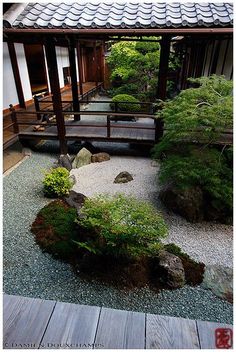 a japanese garden with rocks and plants in it, along with a wooden walkway leading to a pavilion