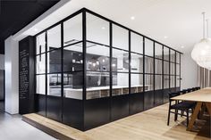 an open kitchen and dining room area in a modern home with wood floors, white walls and black accents