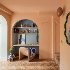 a living room with an arched wall and wooden flooring in the center, along with a chair and bookshelf