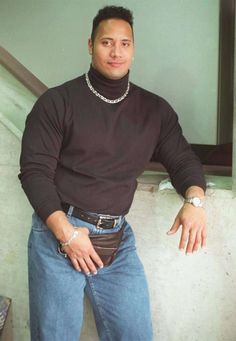 a man in jeans and a turtle neck sweater standing next to a stair case with his hands on his hips