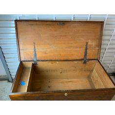 an old wooden box with two metal handles on the top and bottom, sitting in front of a garage door