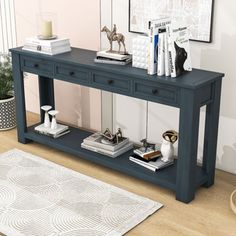 a blue console table with two drawers and books on it in front of a white rug