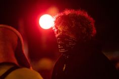 a person wearing a bandana standing in front of a red light