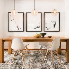 a dining room table with chairs and pictures hanging on the wall above it, in front of a couch