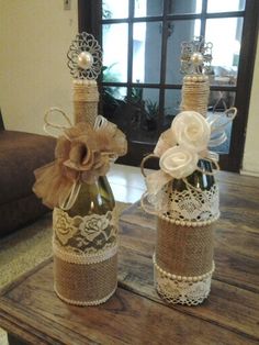 two wine bottles decorated with burlocks and lace are sitting on a coffee table