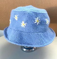 a crocheted blue hat with daisies on the brim is sitting on a table