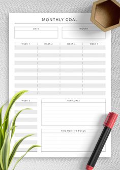 a printable goal sheet next to a pen and plant