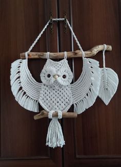 an owl hanging from a wooden door with tassels on it's wings