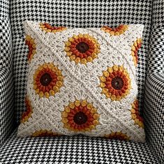 a crocheted sunflower pillow sitting on top of a blue and white chair