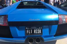 a blue sports car parked in front of a group of people