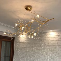 a chandelier hanging from the ceiling in a room with white brick walls and wooden floors