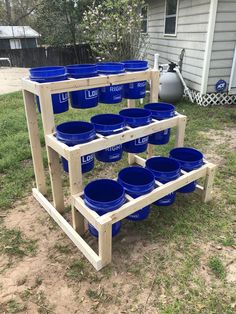 several blue buckets stacked on top of each other in front of a wooden rack