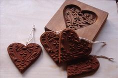 three heart shaped wooden ornaments sitting on top of a white table next to a piece of wood