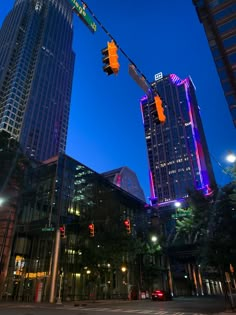 a traffic light hanging over a street next to tall buildings in the city at night