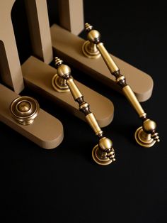 three golden handles and knobs on a black surface