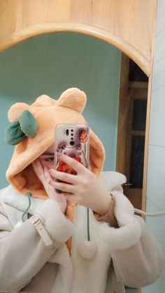 a woman taking a selfie in front of a mirror wearing a teddy bear hat