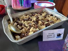 a container filled with lots of cereal next to a sign that says please drop the litter box