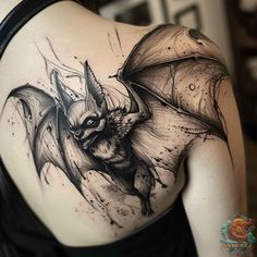 a woman's back with a tattoo design on her shoulder and an image of a bat