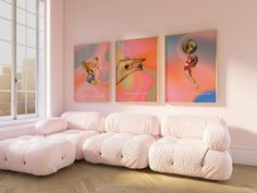 two paintings hang on the wall above a couch in a room with hardwood floors and pink walls