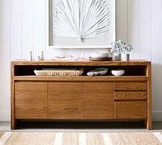 a wooden dresser sitting in front of a white wall with a painting on top of it