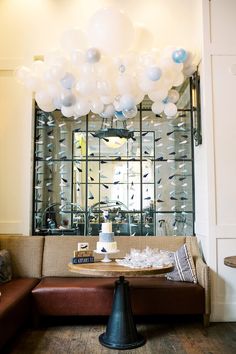 a living room filled with lots of furniture and balloons hanging from the ceiling above it