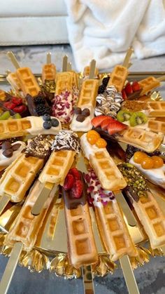 waffles and fruit arranged in a circle on a gold platter with silver serving utensils