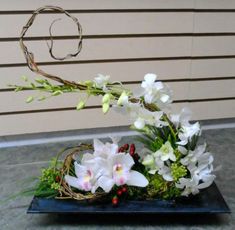 an arrangement of white flowers and greenery in a blue vase on a table next to a wall