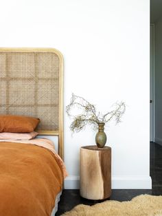 a bed sitting next to a wooden table with a vase on it's side