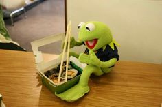 a stuffed animal sitting on top of a wooden table next to some chopsticks