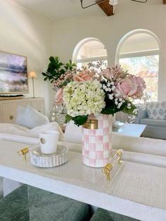 a vase with flowers sitting on top of a table in front of a couch and coffee cup