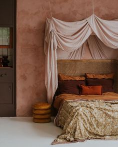 a bedroom with pink walls and an unmade bed in the corner, next to a brown door