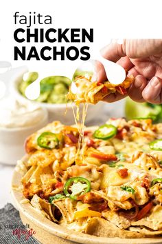 a person is taking a slice of chicken nachos