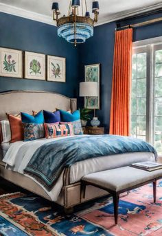 a bedroom with blue walls, orange curtains and a large bed in the middle of it