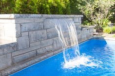 a pool with a waterfall coming out of the top and water running down it's sides