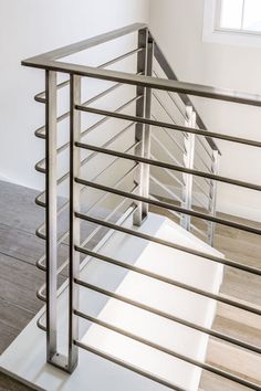 a metal stair railing in an empty room with wood flooring and white painted walls