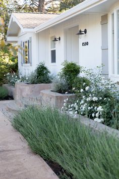 a white house with flowers and bushes in front