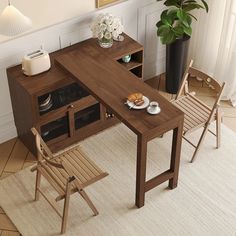 a wooden table with two chairs next to it and a potted plant in the corner