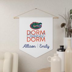 a dorm room sign hanging on the wall next to a chair and vase with flowers