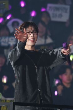 a young man with glasses holding his hands up in the air while standing on stage