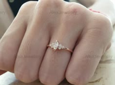 a woman's hand wearing a gold ring with three small white diamonds on it