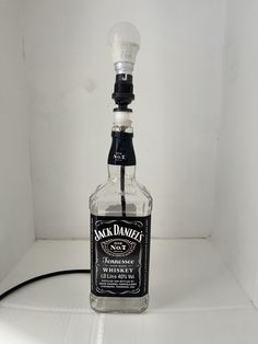 a bottle of jack daniels whiskey sitting on top of a white shelf next to a light bulb