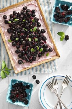 there is a cake with berries on it and two forks next to the dessert plate