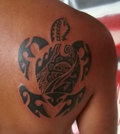 a tattoo on the back of a woman's shoulder and chest, with an image of a turtle