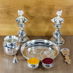 a set of silver items on a wooden table with metal cups and spoons next to each other