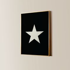 a white star on a black background in a gold frame hanging on a beige wall