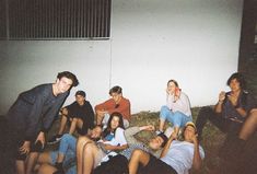 a group of young people sitting next to each other in front of a white wall