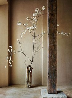 a vase filled with white flowers next to a wooden pole