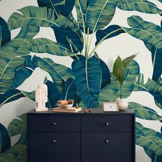 a blue dresser with a plant wallpaper behind it